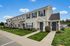 Charming townhouse with classic architecture, manicured lawns, and inviting entrances, set against a blue sky backdrop.