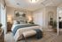 Elegant bedroom featuring a plush bed with teal accents, warm lighting, and stylish decor, offering a serene retreat.