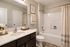Elegant bathroom with modern fixtures, featuring a sleek vanity, spacious mirror, and inviting bathtub, complemented by stylish decor and soft lighting.