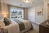 Inviting bedroom interior with a large window offering natural light, elegant decor, and cozy bedding for a serene retreat.