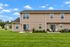 Inviting townhouse exterior with a lush green lawn, charming outdoor seating, and modern design, perfect for relaxing and entertaining.