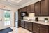 Modern kitchen with elegant dark wood cabinetry, stainless steel appliances, and a view of greenery through glass doors.