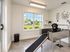 Bright and modern pet washing station with a happy dog in a stainless steel tub, featuring large windows overlooking a lush garden.