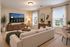 Elegant living room with a neutral palette, cozy sectional sofa, large TV, and natural light from two windows. Stylish decor and indoor plants enhance the inviting atmosphere.
