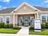 Inviting exterior of Misty Creek Village clubhouse featuring charming rocking chairs, manicured landscaping, and a welcoming entrance.