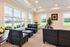 Elegant living room with modern black leather seating, abundant natural light from large windows, and stylish decor.