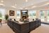Inviting living room with plush leather sectional, cozy fireplace, and bright windows offering scenic views.