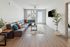 Contemporary living room with sleek gray sectional, vibrant accent pillows, and elegant hardwood floors, bathed in natural light.