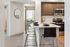 Modern kitchen with sleek appliances, stylish bar seating, and warm wooden cabinetry, perfect for entertaining.