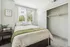Inviting bedroom with cozy bed, modern decor, and ample natural light through large window, offering a serene retreat.