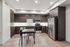 Modern kitchen with sleek dark cabinetry, stainless steel appliances, and a cozy dining area for two.
