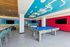Vibrant game room with modern pool table, stylish seating, and beach-themed mural creates an engaging recreational space.