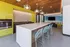 Modern kitchen area with vibrant yellow cabinets, stylish pendant lights, and a large island with turquoise stools offering a bright and inviting atmosphere.