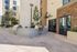 Modern outdoor barbecue area with sleek grills, stylish stone facade, and lush greenery in a luxurious apartment complex.