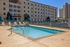 Elegant apartment pool area with comfortable lounge chairs and stylish umbrellas, offering a perfect blend of relaxation and modern architecture.