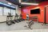 Modern apartment gym with sleek treadmills, an array of weights, and bright red accent wall for a vibrant workout space.