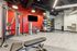 Contemporary fitness center with vibrant red accent wall, featuring a variety of modern gym equipment including weights and exercise balls.