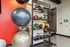 Modern gym corner with vibrant exercise balls, diverse kettlebells, and colorful medicine balls on sleek shelving.