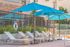Luxurious outdoor lounge area with sleek sun loungers under vibrant blue umbrellas, perfect for relaxation by the poolside.