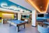 Vibrant communal lounge with a pool table, foosball, modern seating, and a chic bar area.
