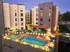 Luxurious rooftop pool area at a modern apartment complex, featuring elegant patio seating and ambient evening lighting.