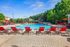 Luxurious outdoor swimming pool surrounded by vibrant red loungers and lush greenery, offering a perfect summer retreat.