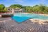 Luxurious outdoor pool area with a refreshing design, surrounded by lush greenery and vibrant red umbrellas, perfect for relaxing retreats.