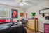 Cozy bedroom with vibrant decor, featuring a comfortable bed, stylish desk, and natural light pouring through large windows.