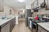 Modern kitchen with sleek granite countertops, stainless steel appliances, and elegant wood flooring leading to a stylish dining area.