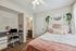 Inviting bedroom with a chic design, featuring a cozy bed with blush accents, modern workspace, and lush greenery for a serene atmosphere.