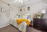 Cozy bedroom with elegant decor, featuring a plush bed with vibrant yellow accents, stylish artwork, and a modern dresser with decorative elements.