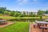 Serene apartment complex overlooking a tranquil pond with lush greenery and inviting picnic area, perfect for outdoor relaxation.