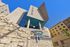 Modern urban building with striking architectural design, highlighted by geometric shapes and stone textures under a clear blue sky.