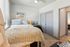 Cozy bedroom with soft, neutral decor, featuring a plush bed, elegant vanity, and calming natural light from large windows.