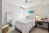 Bright and cozy bedroom featuring a comfortable double bed, modern ceiling fan, and a stylish workspace with a desk and shelving.