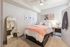 Cozy bedroom featuring a comfortable bed with plush bedding, stylish decor, and a large framed mirror enhancing the room's elegance.