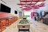 Vibrant game room featuring a foosball table, arcade machines, and stylish bar seating with a unique geometric ceiling design.