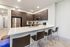 Sleek modern kitchen with stainless steel appliances, dark wood cabinets, and a spacious white countertop island with bar seating.