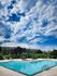 Inviting outdoor swimming pool with lounge chairs, set against a backdrop of lush greenery and picturesque skies.
