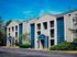 Charming apartment complex with modern architectural design, featuring spacious balconies, nestled in a lush, well-maintained landscape under a clear blue sky.