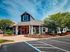 Charming apartment complex entrance featuring vibrant landscaping, colorful flowers, and a welcoming porch under a clear blue sky.