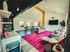 Vibrant open living space with contemporary decor, featuring a bold fuchsia rug, stylish seating, and sleek kitchen area with modern lighting.
