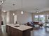 the simon at founders row. kitchen island with sink overlooking living area with couch, tables, and hardwood floors.