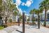 Vibrant outdoor area featuring hammocks under palm trees beside a sparkling pool, surrounded by modern apartment buildings.