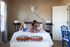 Inviting bedroom with modern decor, featuring cozy bedding, stylish lamps, and elegant wall art, enhanced by natural light.