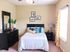 Charming bedroom with elegant decor, featuring a cozy bed with colorful pillows, stylish dresser, and bright natural light from a large window.