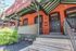 Charming brick townhouse with elegant green accents and a welcoming front porch, perfect for enjoying sunny days.