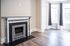Elegant apartment room featuring a classic fireplace, large bay windows with natural light, and stylish hardwood flooring.