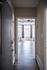 Inviting hallway leading to a bright living room with large windows and elegant hardwood flooring.