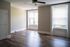 Bright spacious room with elegant wood flooring, large windows, and modern ceiling fan, ideal for a welcoming living space.
